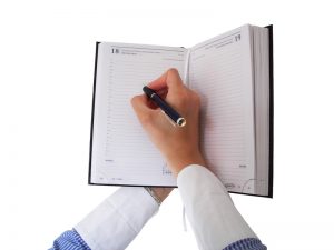 woman's hands writing in schedule