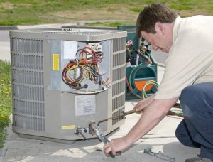 An air conditioning technician welds a connection prior to installing AC unit.