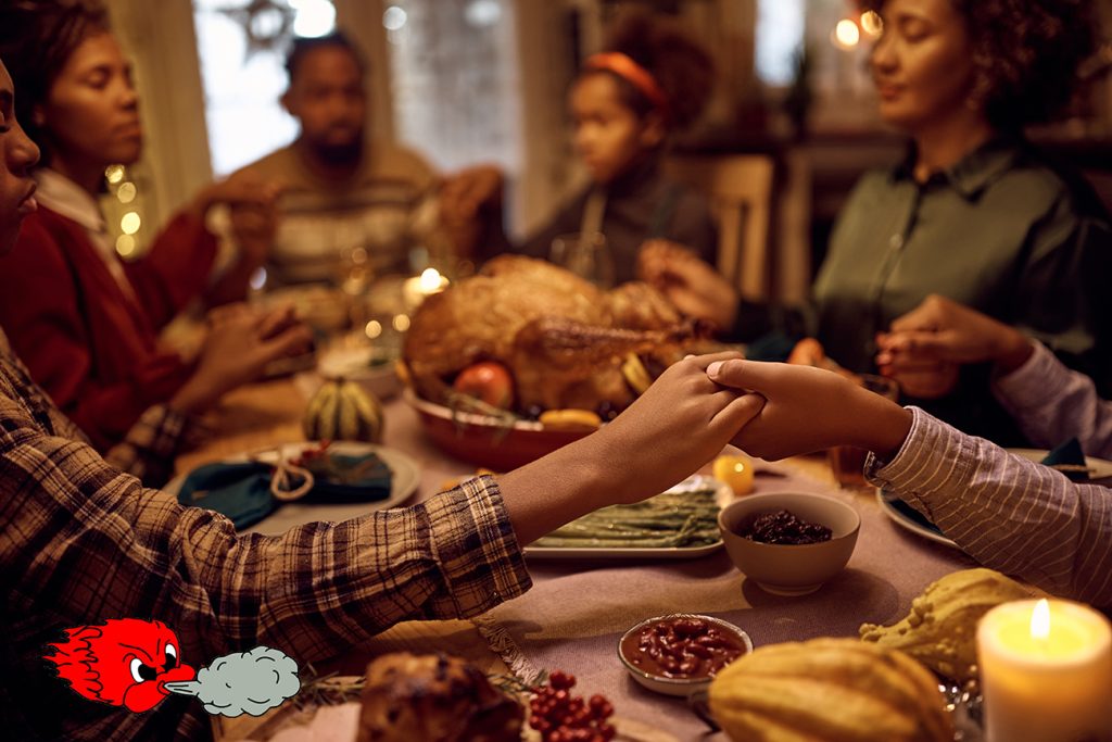 Close up of black brothers holding hands while praying with their family during dinner on Thanksgiving