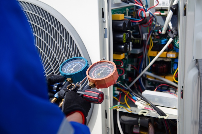 The air conditioner technician is using a gauge to measure the refrigerant pressure. air compressor.
