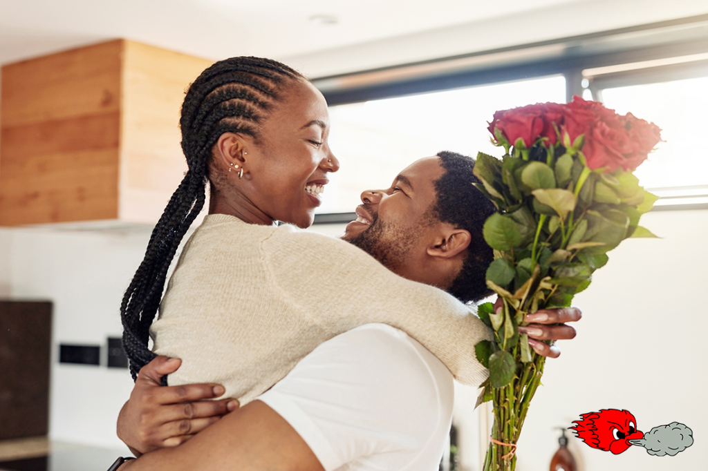 A young man surprising his wife with a bunch of flowers at home